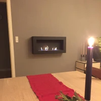 Brede zwarte biohaard met twee branders voor aan de muur.