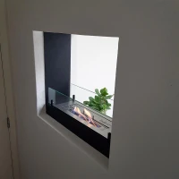 slanke bio-ethanolhaard in zwart met glazen raampanelen waardoor deze transparant is. Voor muurintegratie.