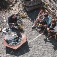 H&ouml;fats TRIPLE 120 Vuurkorf in Cortenstaal met brandende houtblokken, geplaatst op een witte ondergrond.
