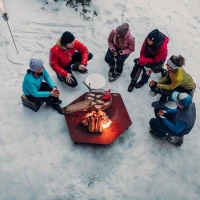 H&ouml;fats TRIPLE 120 Vuurkorf in Cortenstaal met brandende houtblokken, geplaatst op een witte ondergrond.
