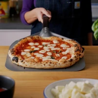 Geperforeerde aluminium pizzaschep van 33 cm met zwarte afneembare handgreep